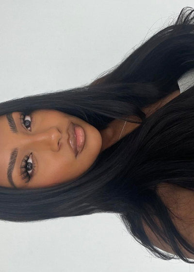 Close-up of a person with long black hair on a light gray background
